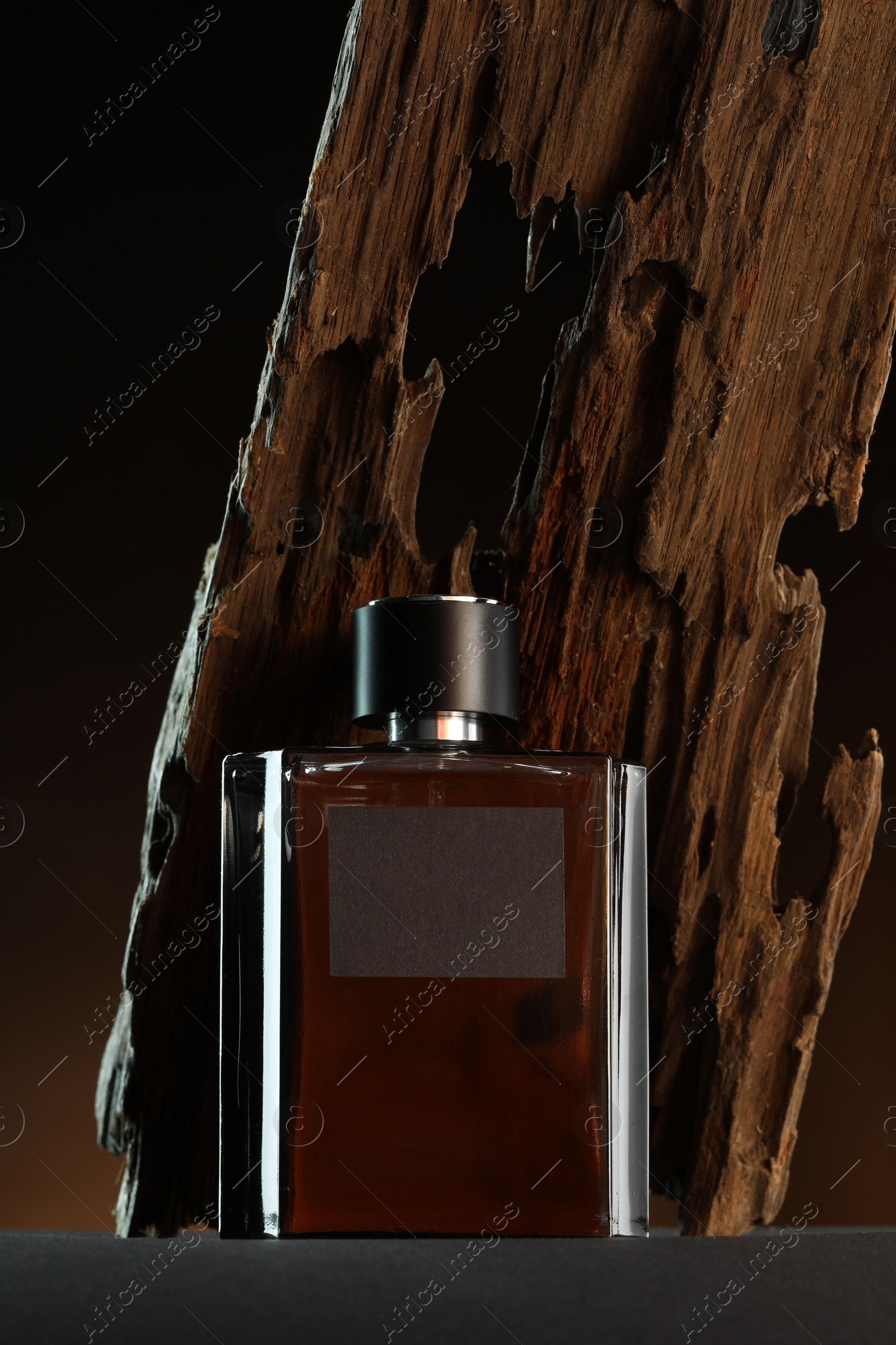 Photo of Luxury men`s perfume in bottle on grey table against dark background