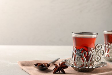 Photo of Glasses of traditional Turkish tea in vintage holders and anise stars on table. Space for text