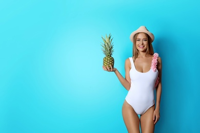 Photo of Sexy young woman in bikini with pineapple on color background