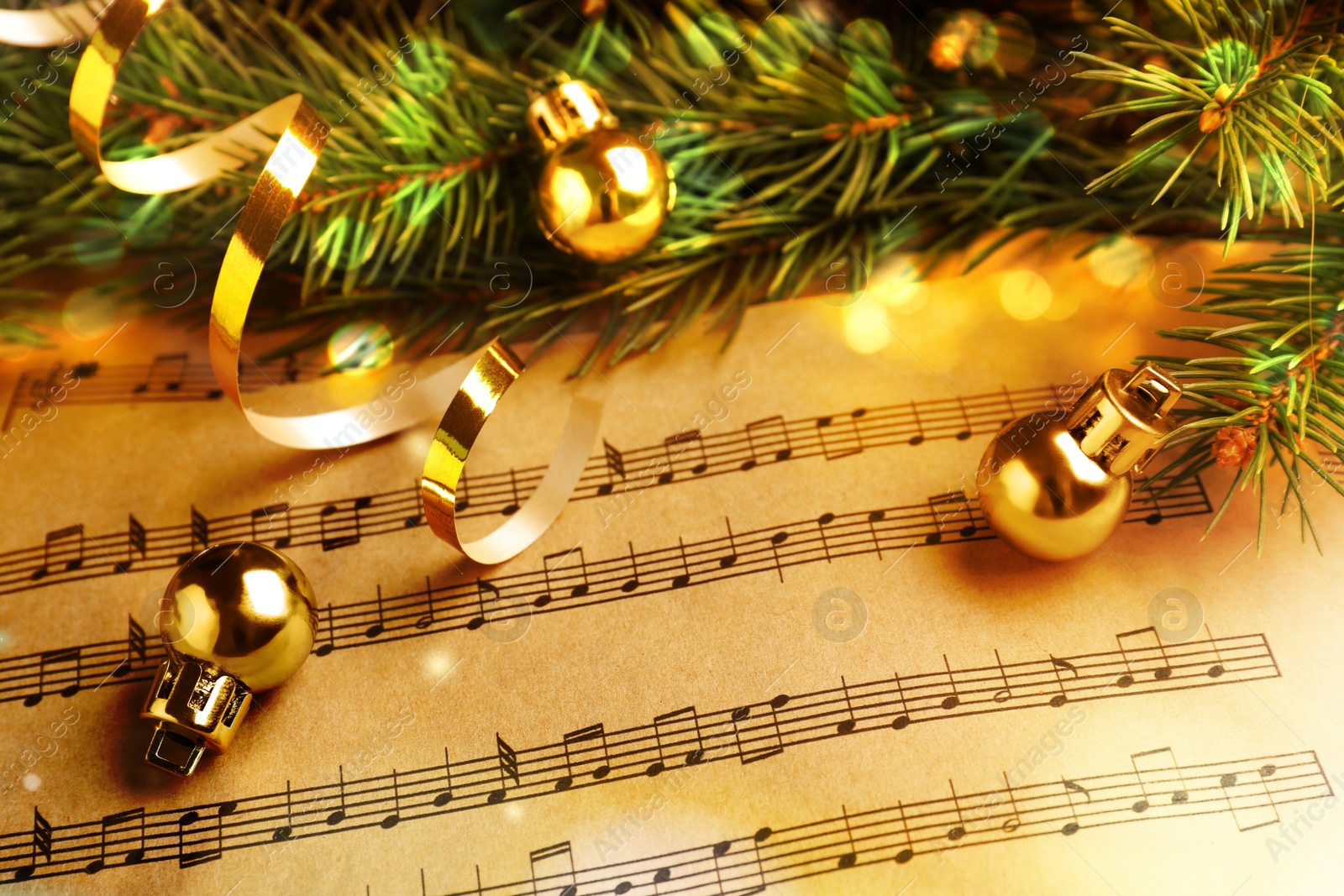 Image of Fir branches, golden streamer and Christmas balls on music sheets, closeup