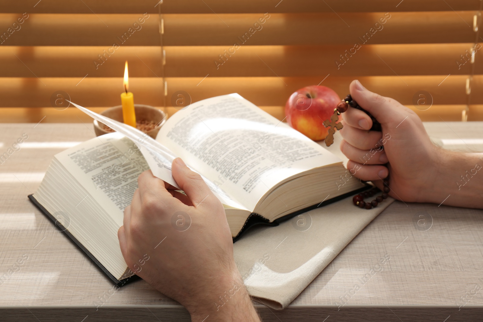 Photo of Man with Bible praying near window indoors, closeup. Great Lent season