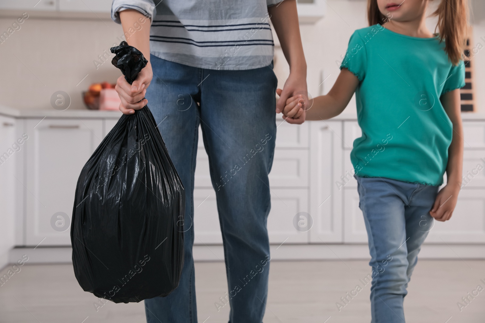 Photo of Woman holding bin bag full of garbage in kitchen, closeup