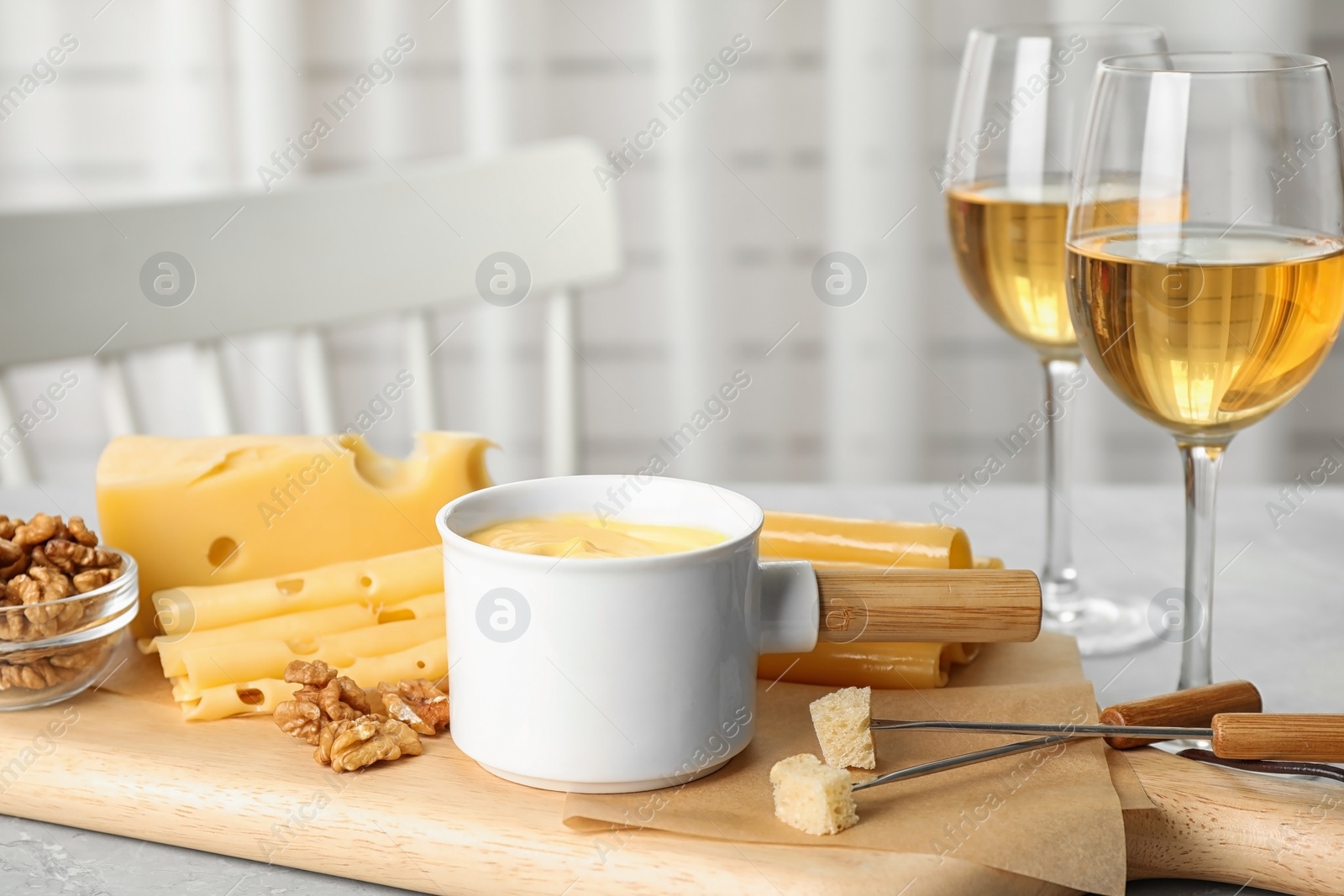 Photo of Pot of tasty cheese fondue served on white wooden table indoors, space for text