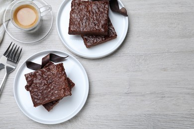 Delicious chocolate brownies served on white wooden table, flat lay. Space for text