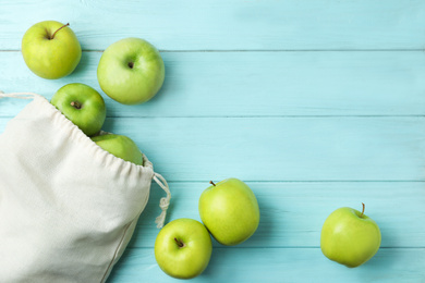 Photo of Cotton eco bag with apples on light blue wooden background, flat lay. Space for text
