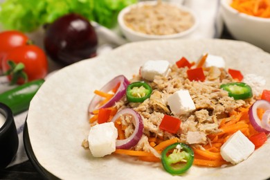 Photo of Delicious tortilla with tuna, vegetables and cheese on table, closeup. Cooking shawarma