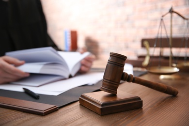 Photo of Judge working at table in office, focus on gavel. Law and justice concept