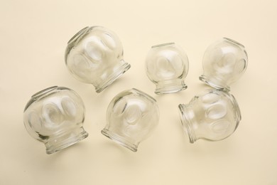 Photo of Many glass cups on beige background, flat lay. Cupping therapy