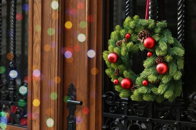 Beautiful Christmas wreath hanging on wooden door, space for text