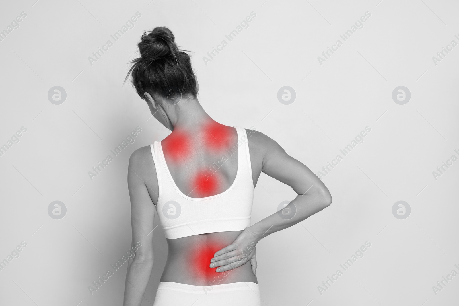 Image of Woman suffering from back pain on light background