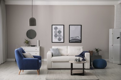 Stylish living room interior with white sofa, armchair and small coffee table