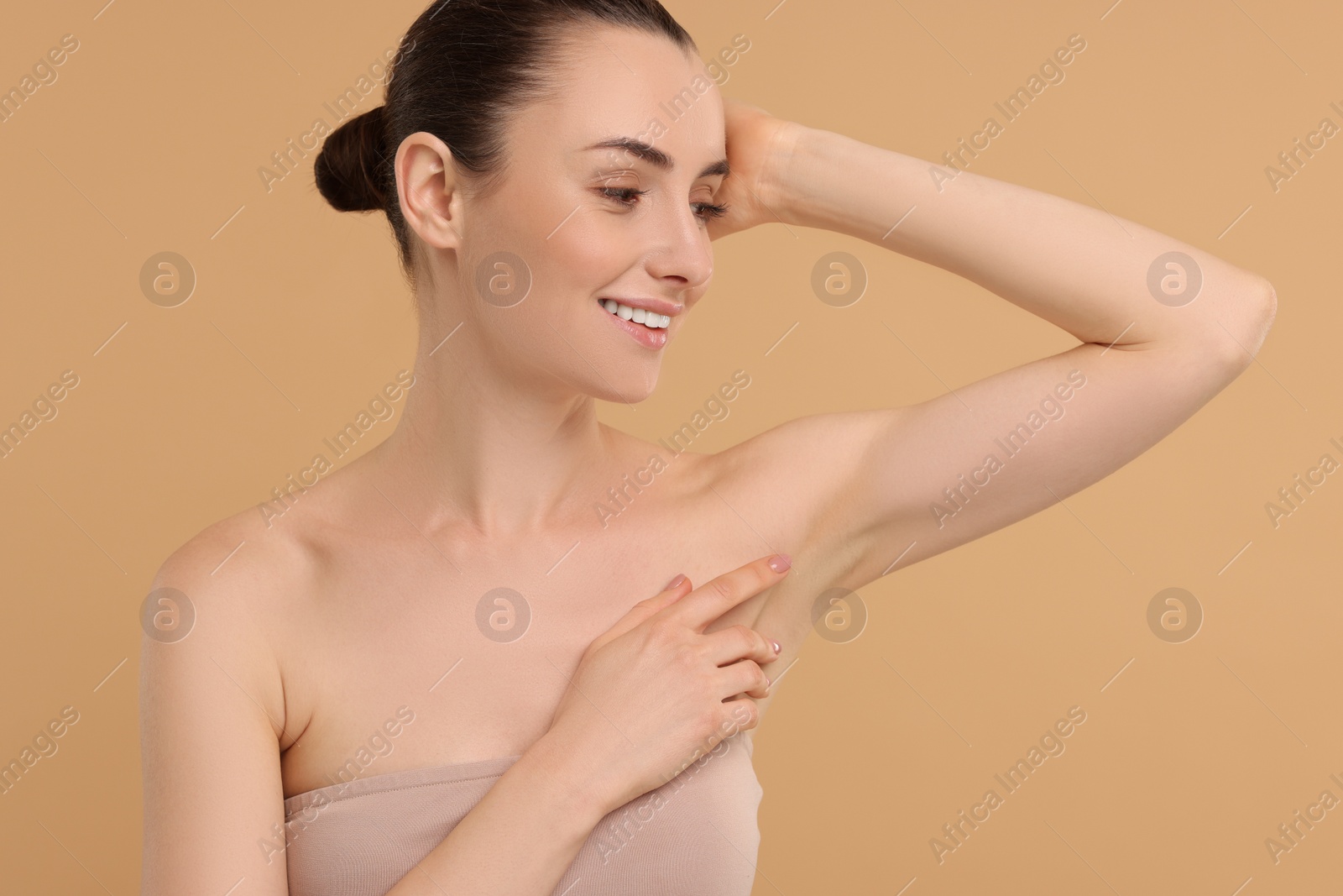 Photo of Beautiful woman showing armpit with smooth clean skin on beige background