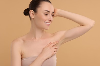 Beautiful woman showing armpit with smooth clean skin on beige background