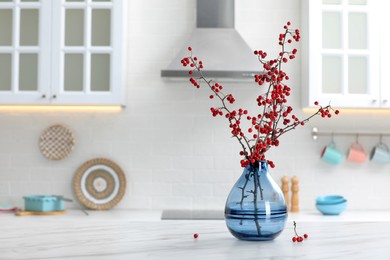 Photo of Hawthorn branches with red berries on table in kitchen, space for text