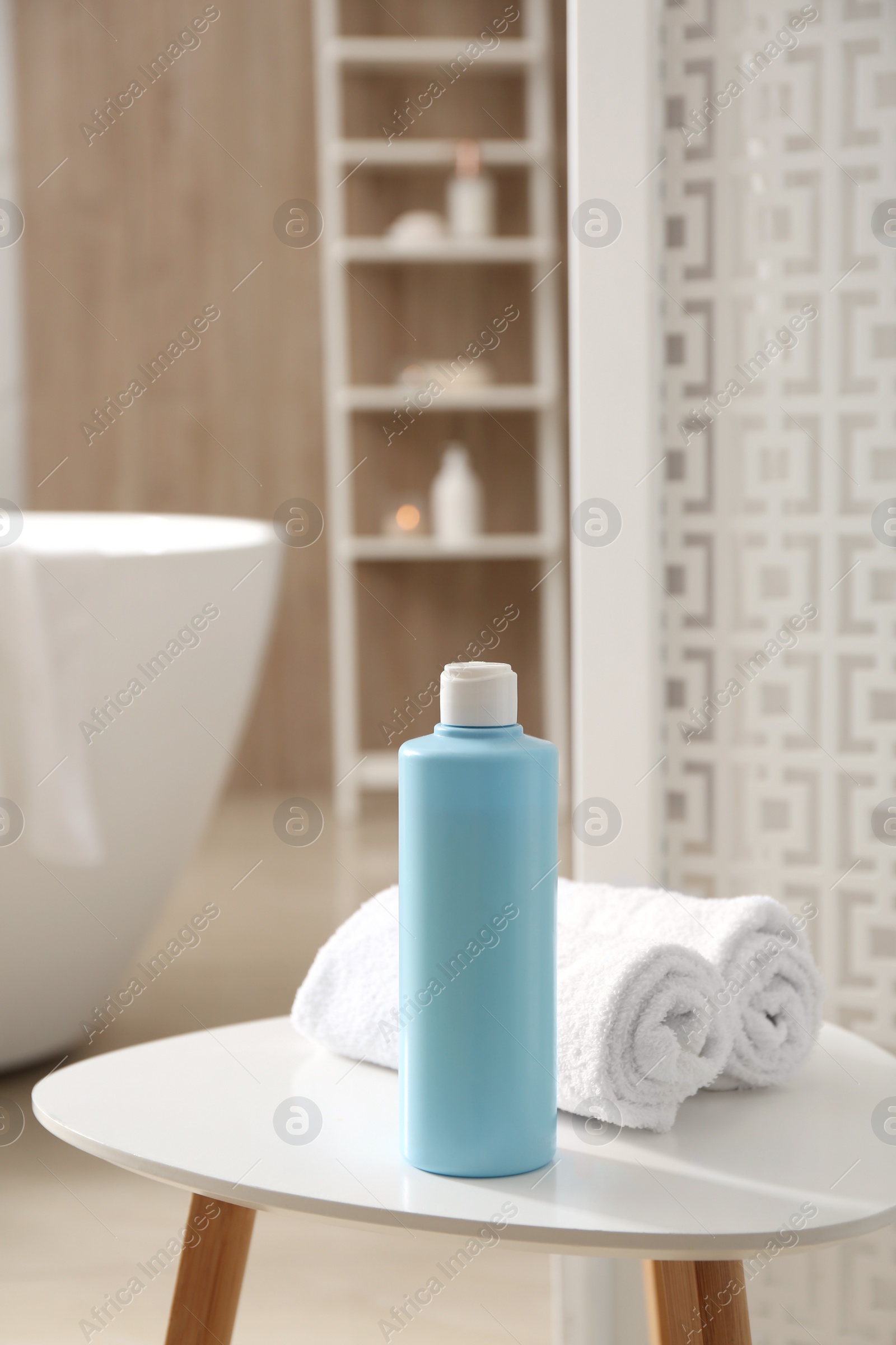 Photo of Bottle of shower gel and fresh towels on white table in bathroom