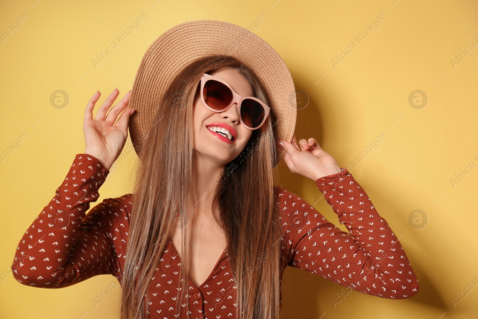 Photo of Young woman wearing stylish sunglasses and hat on yellow background