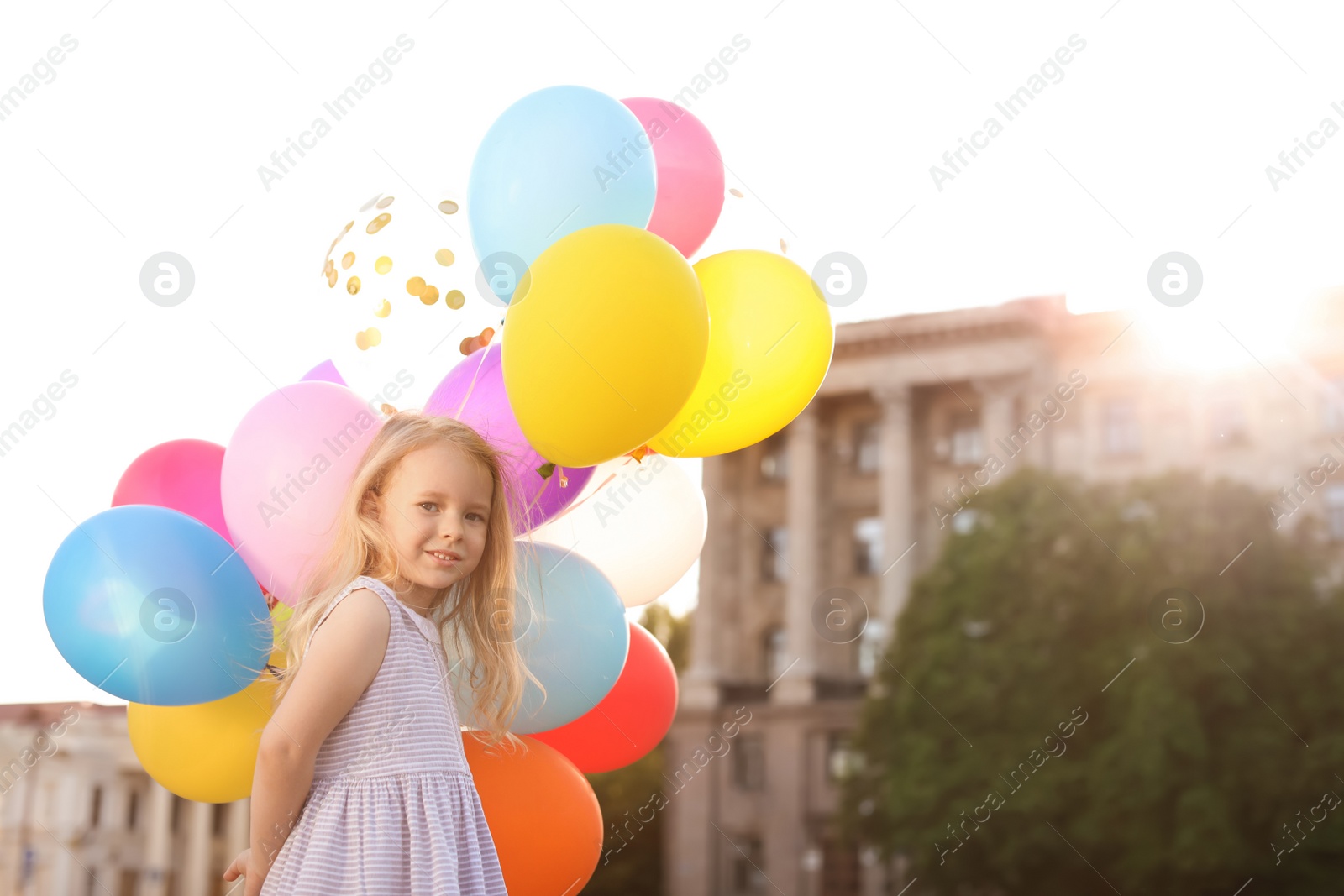 Photo of Cute little girl with colorful balloons outdoors on sunny day