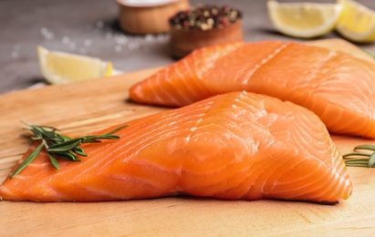 Photo of Wooden board with tasty salmon fillet on table, closeup