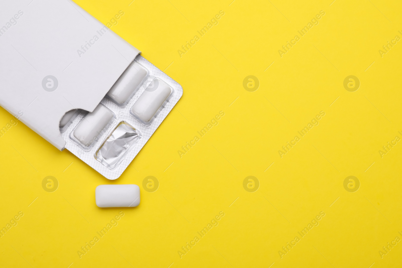 Photo of Blister with chewing gums on yellow background, top view. Space for text