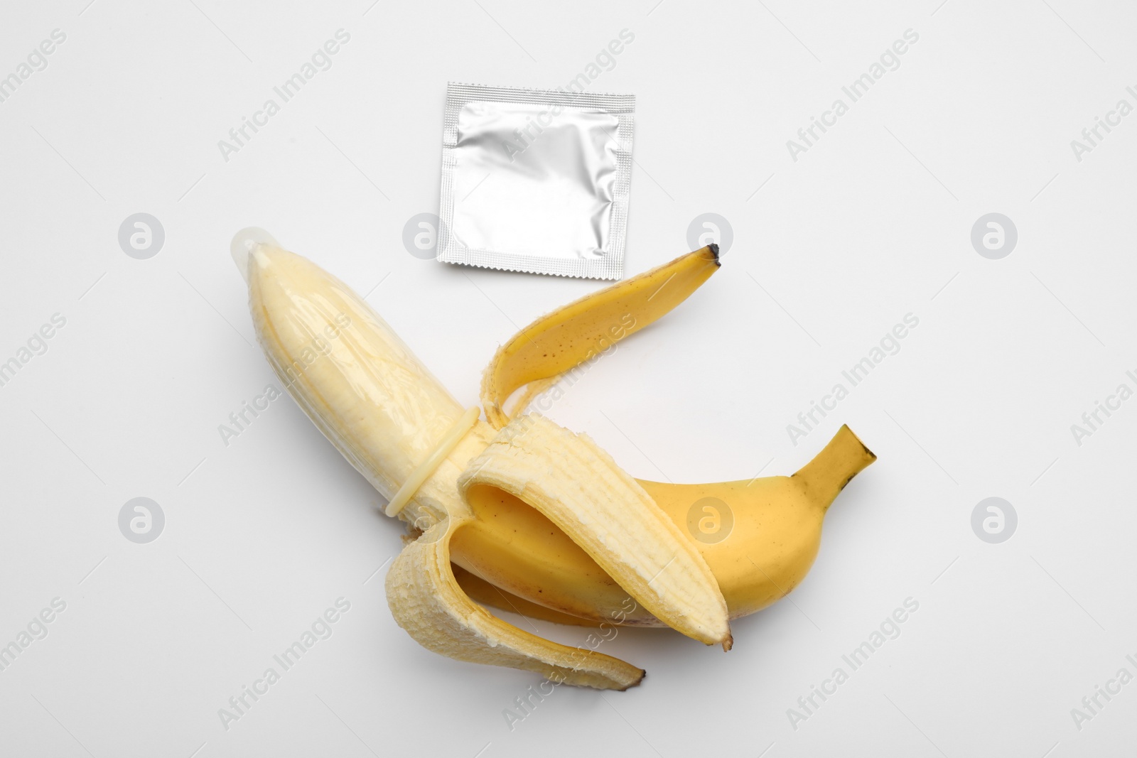 Photo of Banana with condom on white background, top view. Safe sex