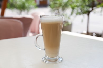 Glass with delicious coffee on white table in outdoor cafe
