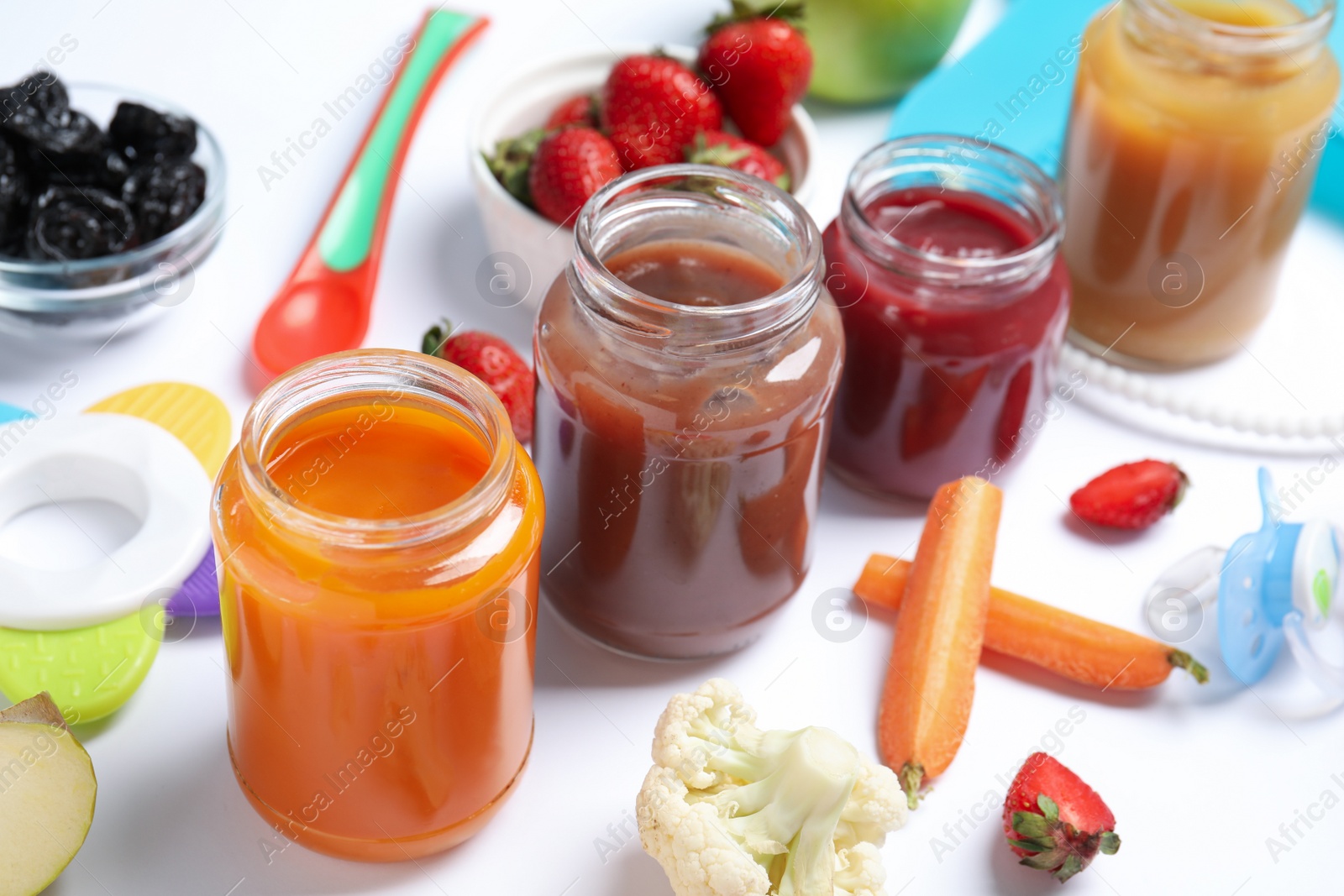 Photo of Jars with healthy baby food and ingredients on white background