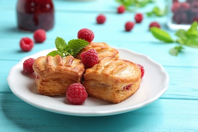 Photo of Fresh delicious puff pastry with sweet berries served on light blue wooden table