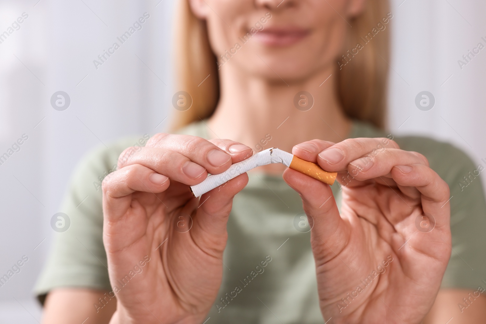 Photo of Woman breaking cigarette on light background, selective focus. Quitting smoking concept