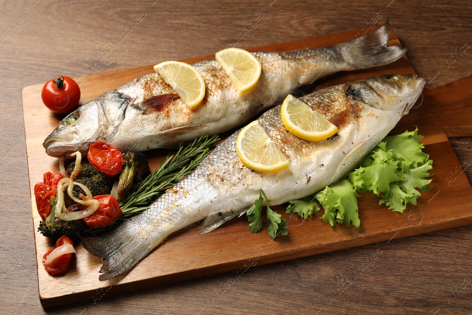 Photo of Delicious baked fish and vegetables on wooden table