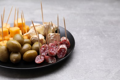 Toothpick appetizers. Pieces of cheese, sausage and olives on light grey table. Space for text