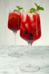 Photo of Delicious Red Sangria with fruits on white marble table