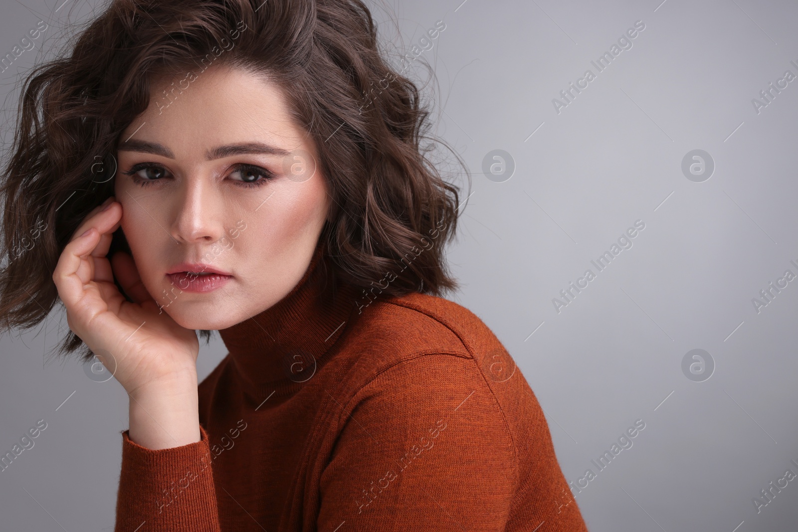 Photo of Portrait of beautiful young woman with wavy hairstyle on grey background. Space for text