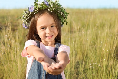Cute little girl wearing flower wreath outdoors. Child spending time in nature