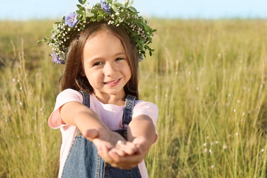 Photo of Cute little girl wearing flower wreath outdoors. Child spending time in nature