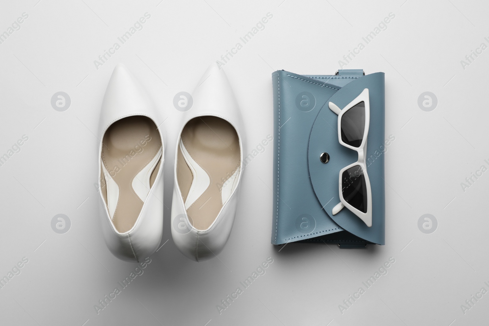 Photo of Stylish woman's bag, sunglasses and shoes on light background, flat lay