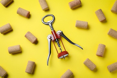Corkscrew and wine bottle stoppers on yellow background, flat lay