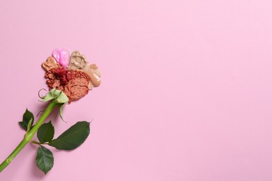 Photo of Flower made of makeup products on pink background, top view. Space for text