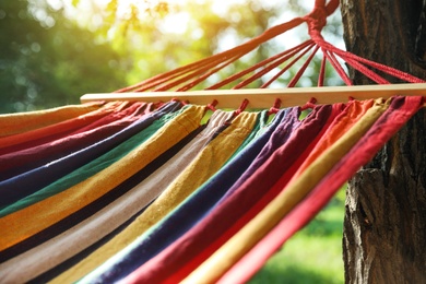 Bright comfortable hammock hanging in green garden, closeup