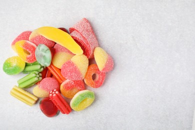 Pile of tasty colorful jelly candies on white table, flat lay. Space for text