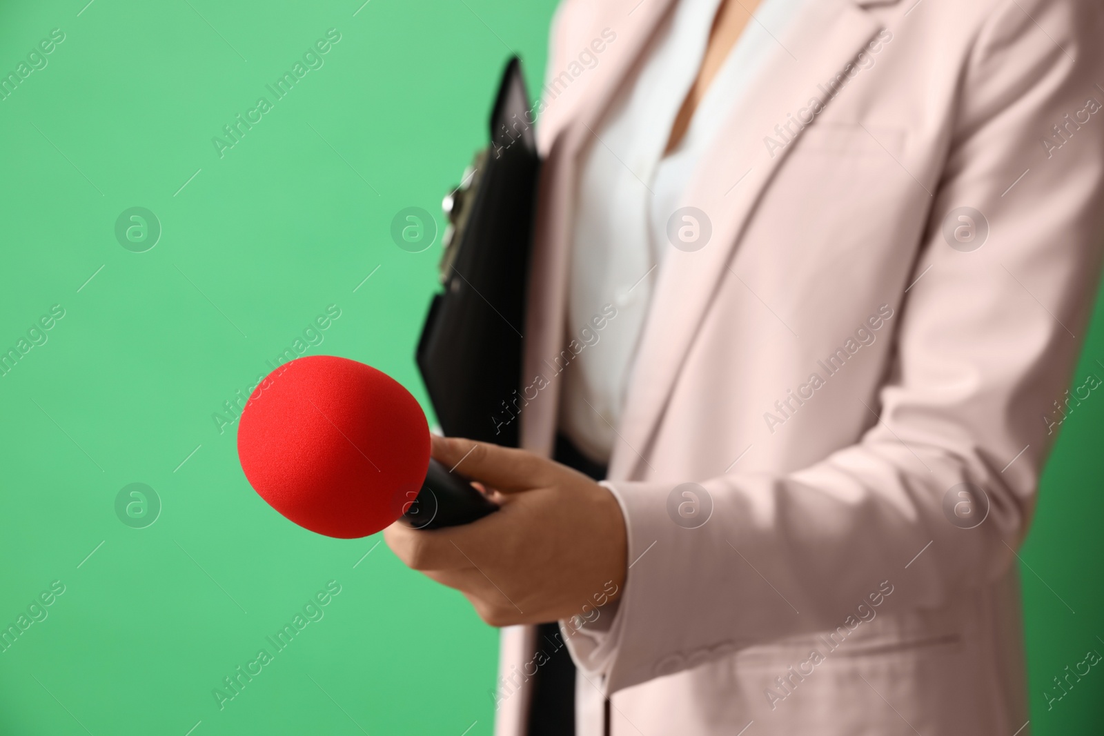 Photo of Journalist with microphone and clipboard on green background, closeup