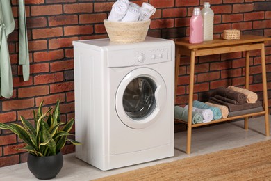 Photo of Washing machine and wooden console table with terry towels indoors. Laundry room interior design