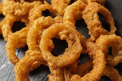 Homemade crunchy fried onion rings on slate plate, closeup