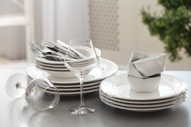 Photo of Setclean dishware, cutlery and wineglasses on table indoors