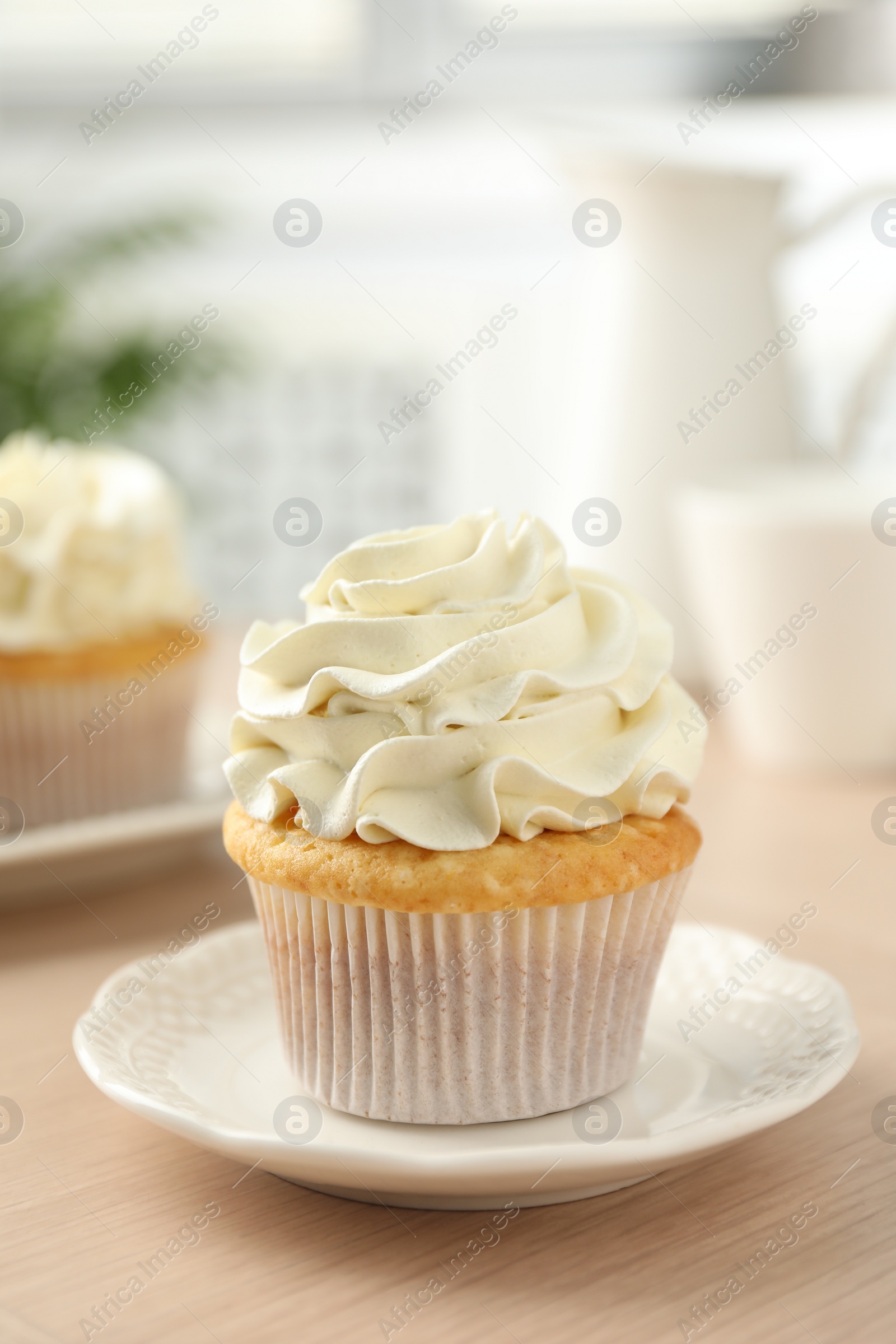 Photo of Tasty cupcake with vanilla cream on light wooden table, closeup