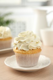 Photo of Tasty cupcake with vanilla cream on light wooden table, closeup