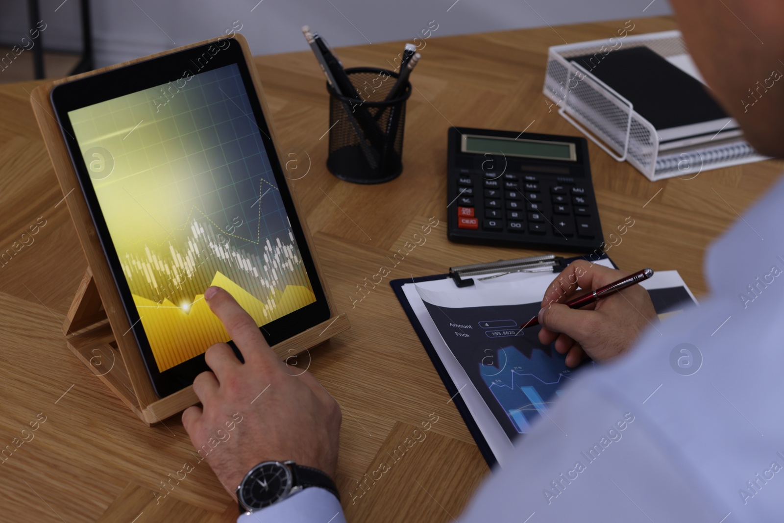 Photo of Businessman working with tablet and chart at table, closeup. Forex trading