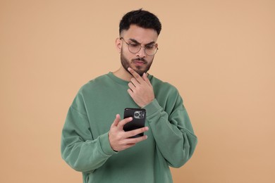 Photo of Handsome young man using smartphone on beige background