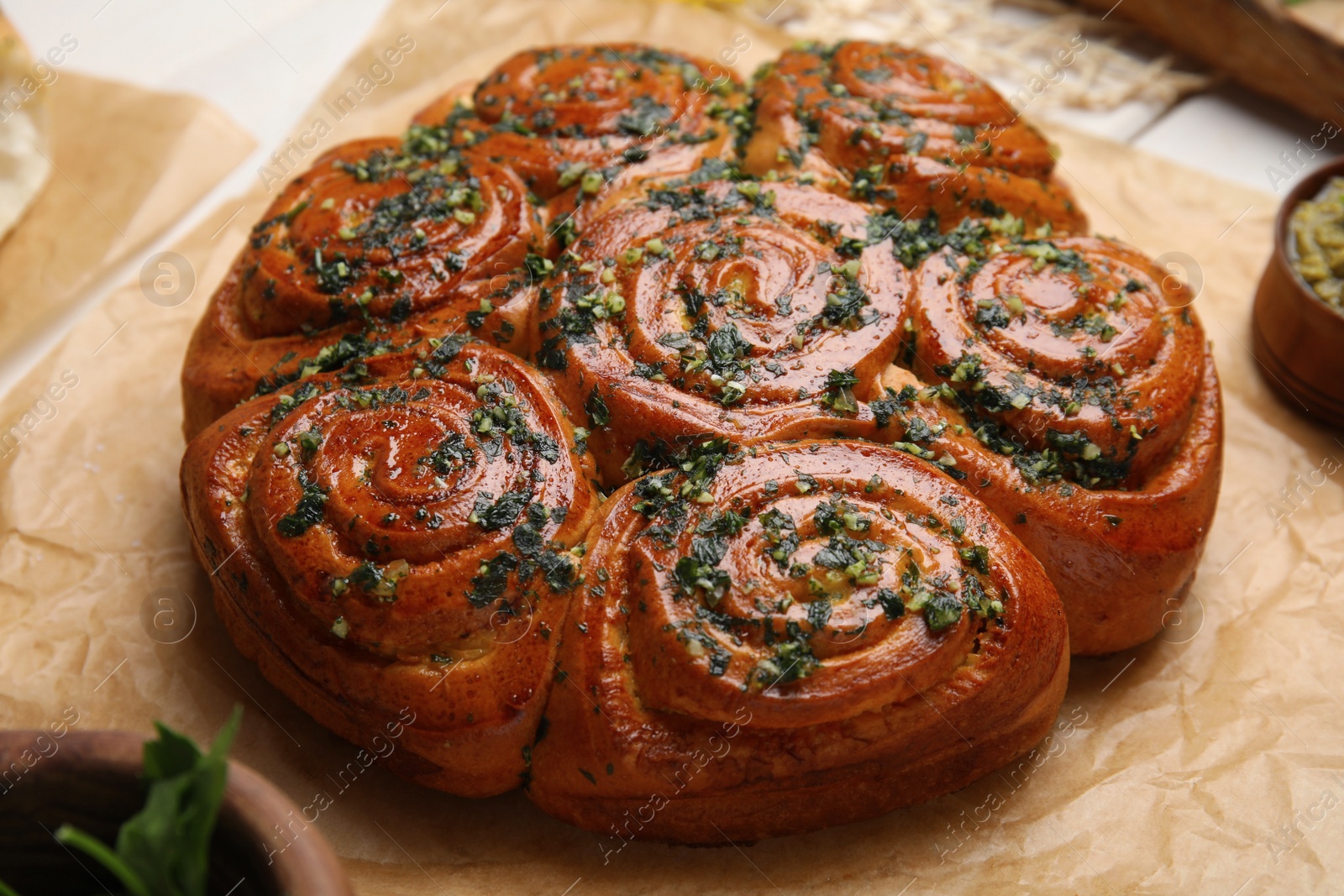 Photo of Traditional pampushka rolls with garlic and herbs on table, closeup