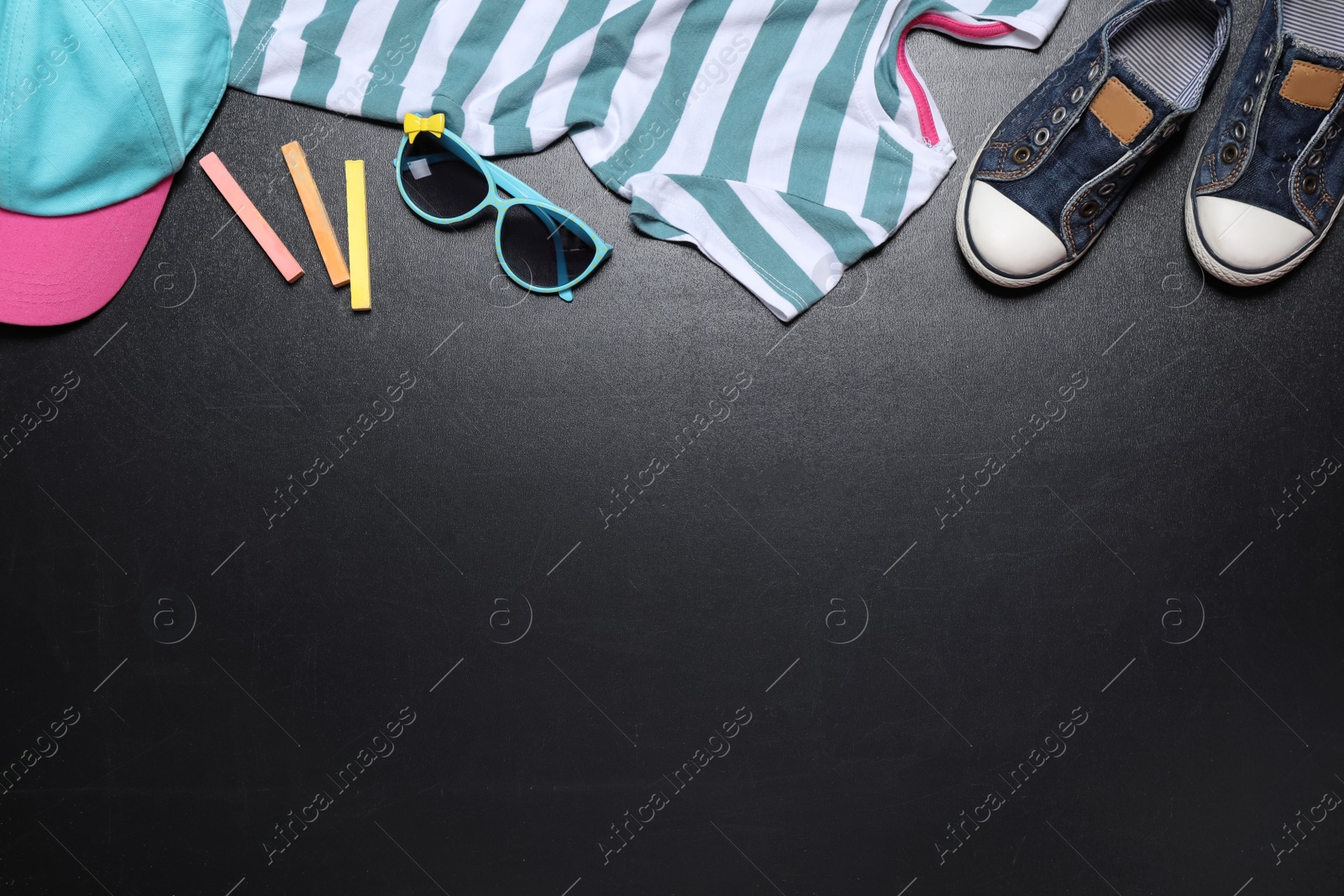 Photo of Flat lay composition with child's shoes on blackboard, space for text. School holidays