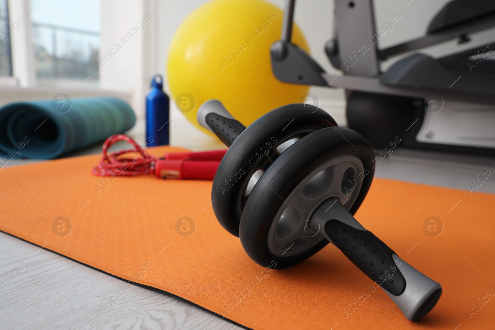 Photo of Ab roller and sport equipment near elliptical machine in gym